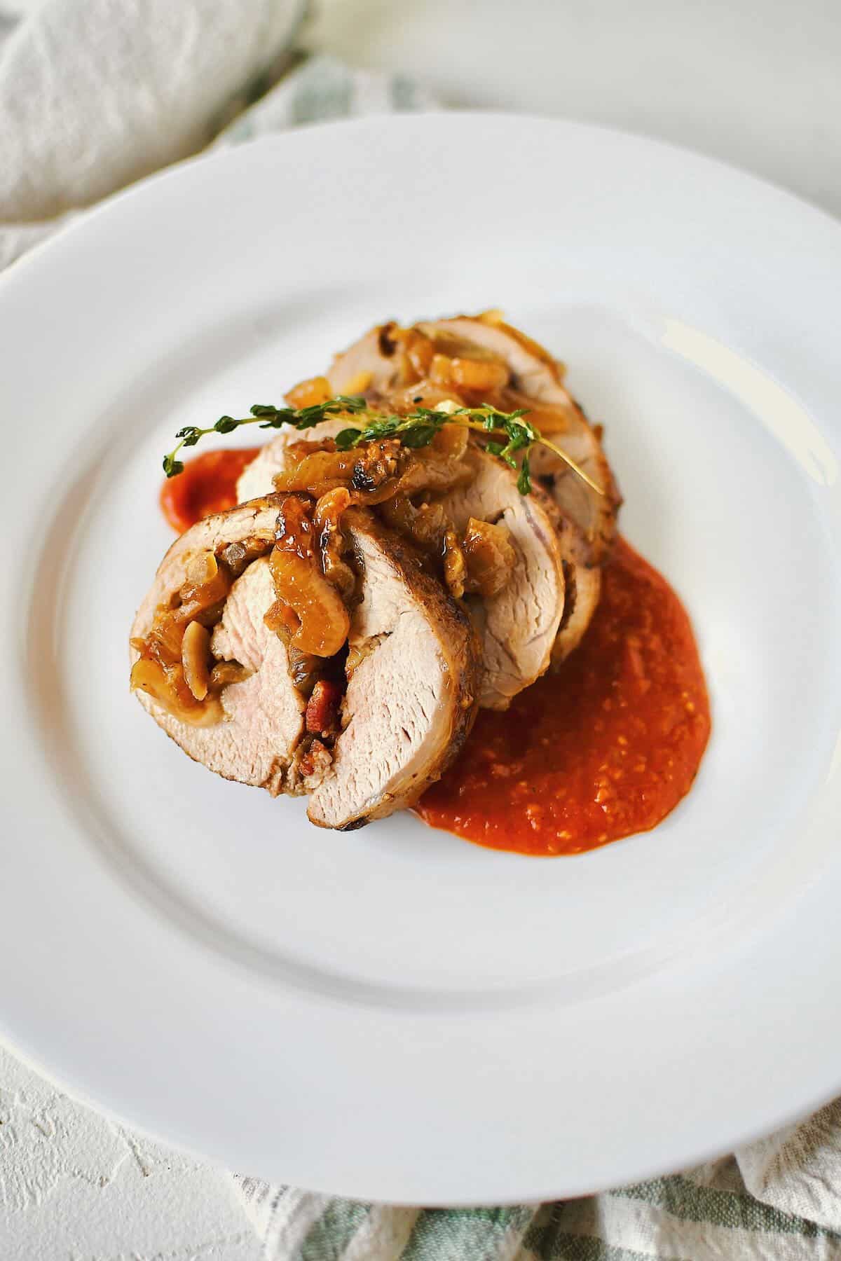 A few slices of Stuffed Pork Tenderloin served over roasted tomato vinaigrette. 