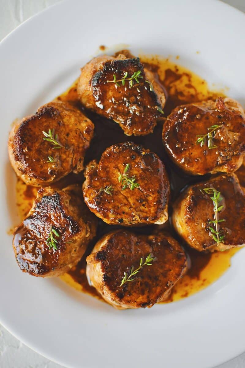 Pork Tenderloin Medallions basted with sauce and resting on a plate ready to eat.