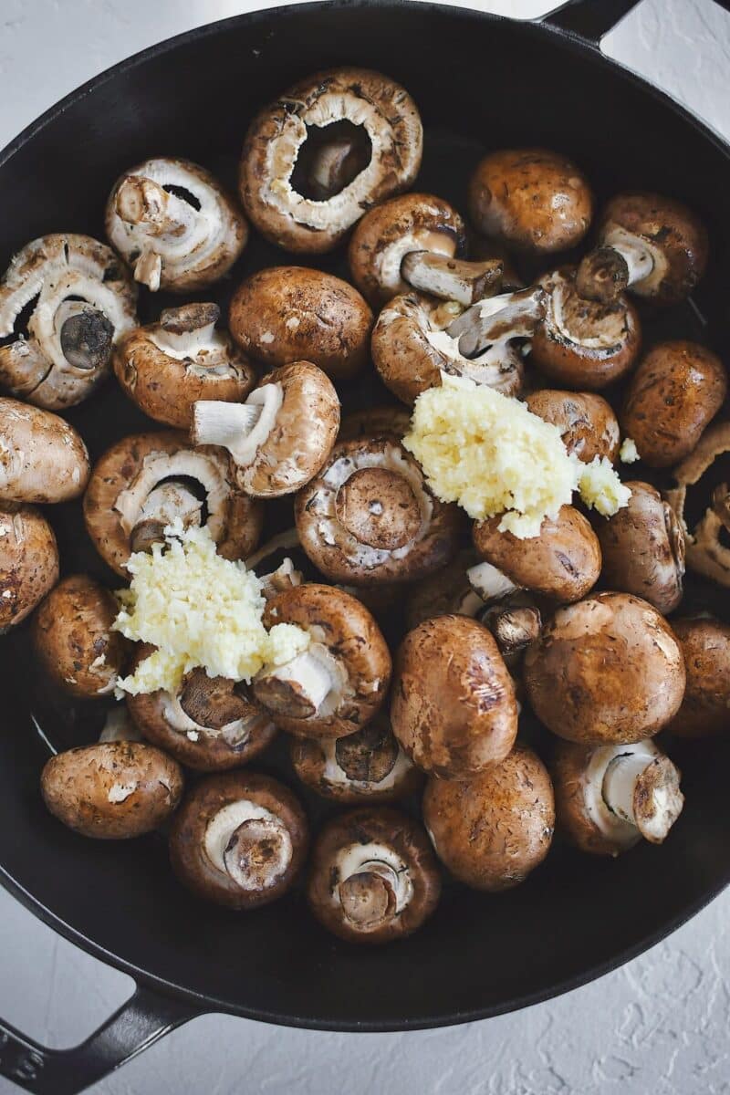 Placing the mushrooms in a hot pan with oil and garlic to steam.