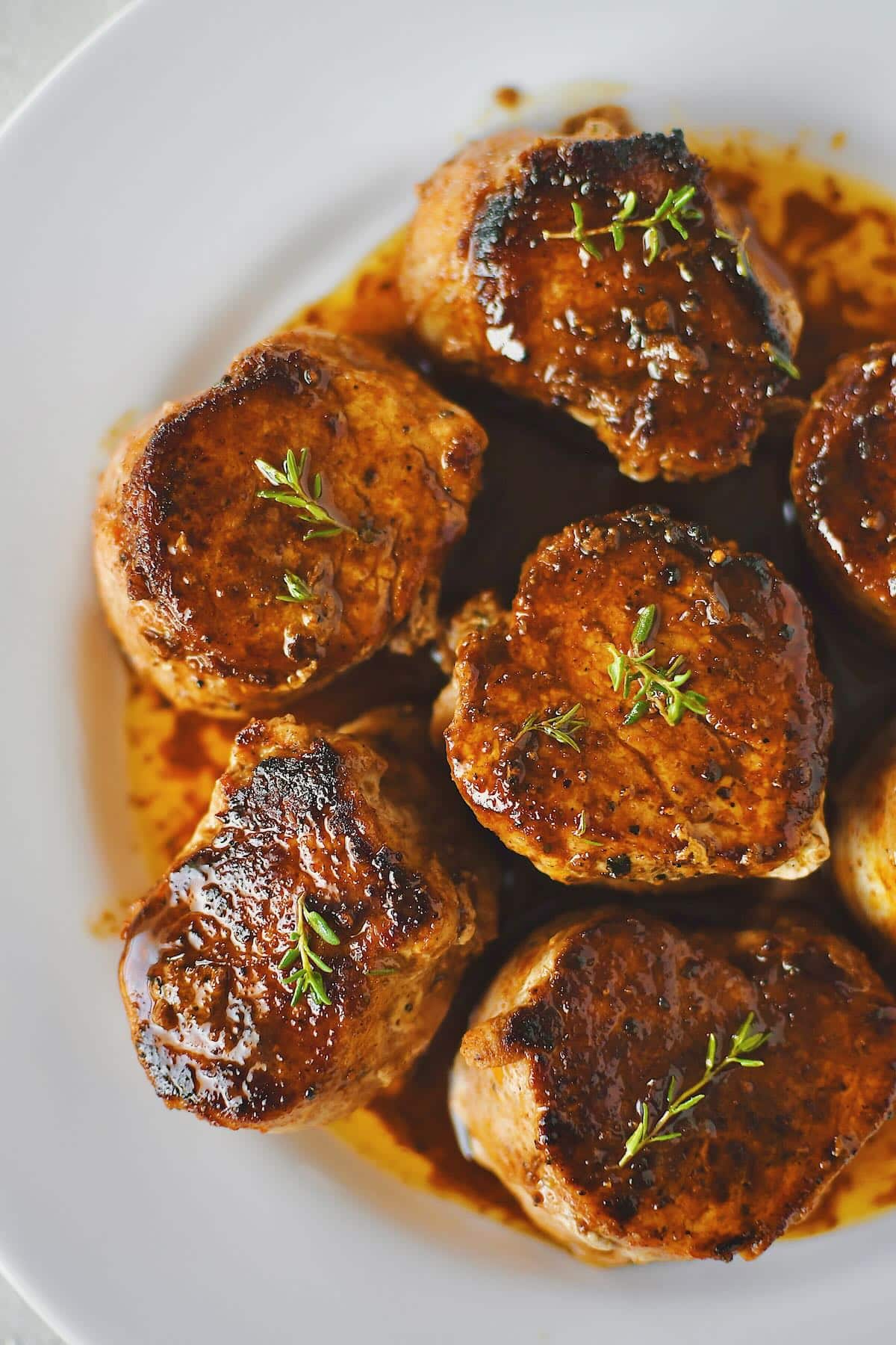 Pork Tenderloin Medallions basted with sauce and resting on a plate ready to eat.