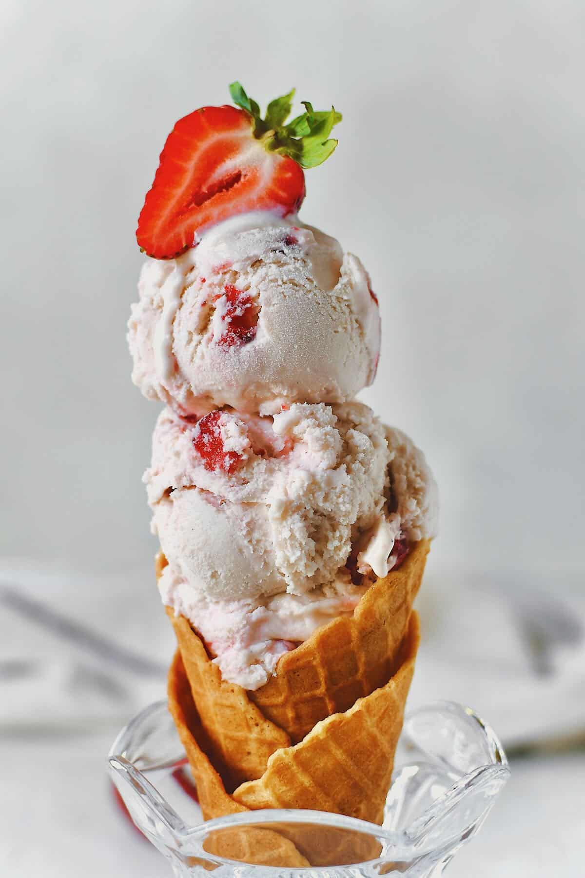 Strawberry Ice Cream served in a cone standing in a sunday dish.