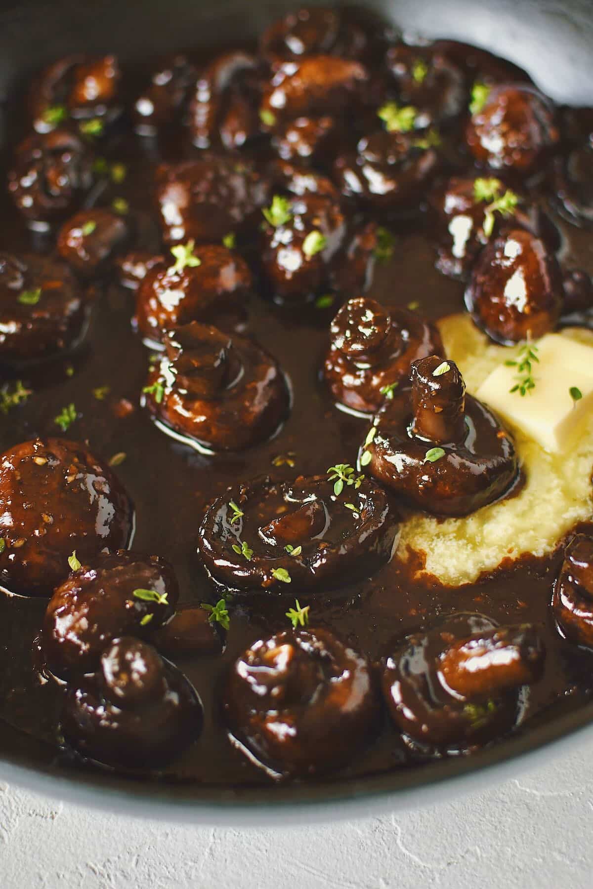 Finishing the mushrooms with a little more butter to make them extra rich and glossy. Ready to eat and topped with some thyme leaves.