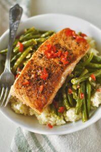 Pan Seared Salmon fillets nestled served over sauteed green beans and rice.