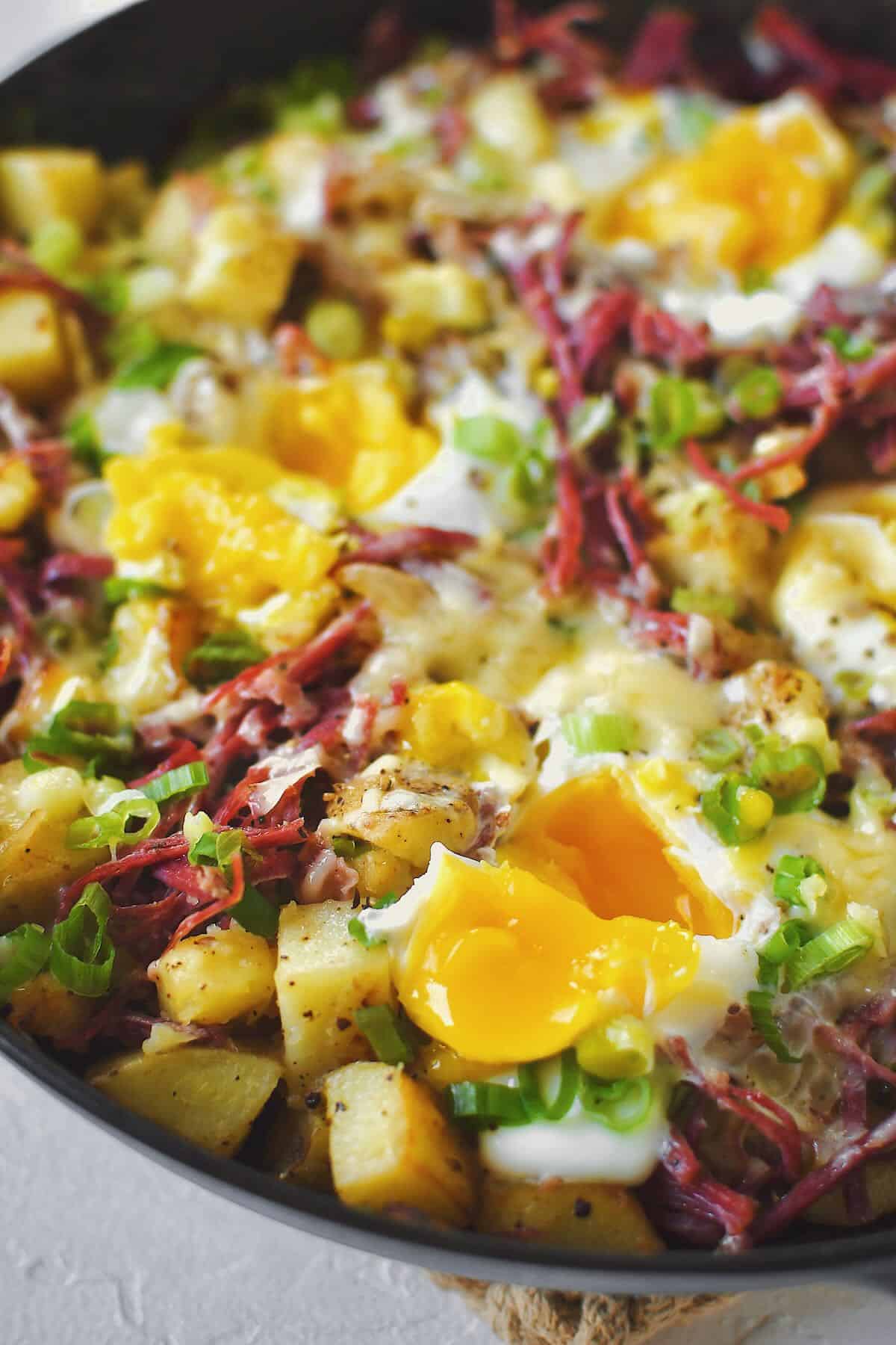 Eggs cracked into the corned beef hash, and cooked just till the whites have set, yolks opened to run out into the hash.