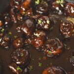 The demi-glace has been stirred in and boiled till it has begun to cling to the mushrooms.