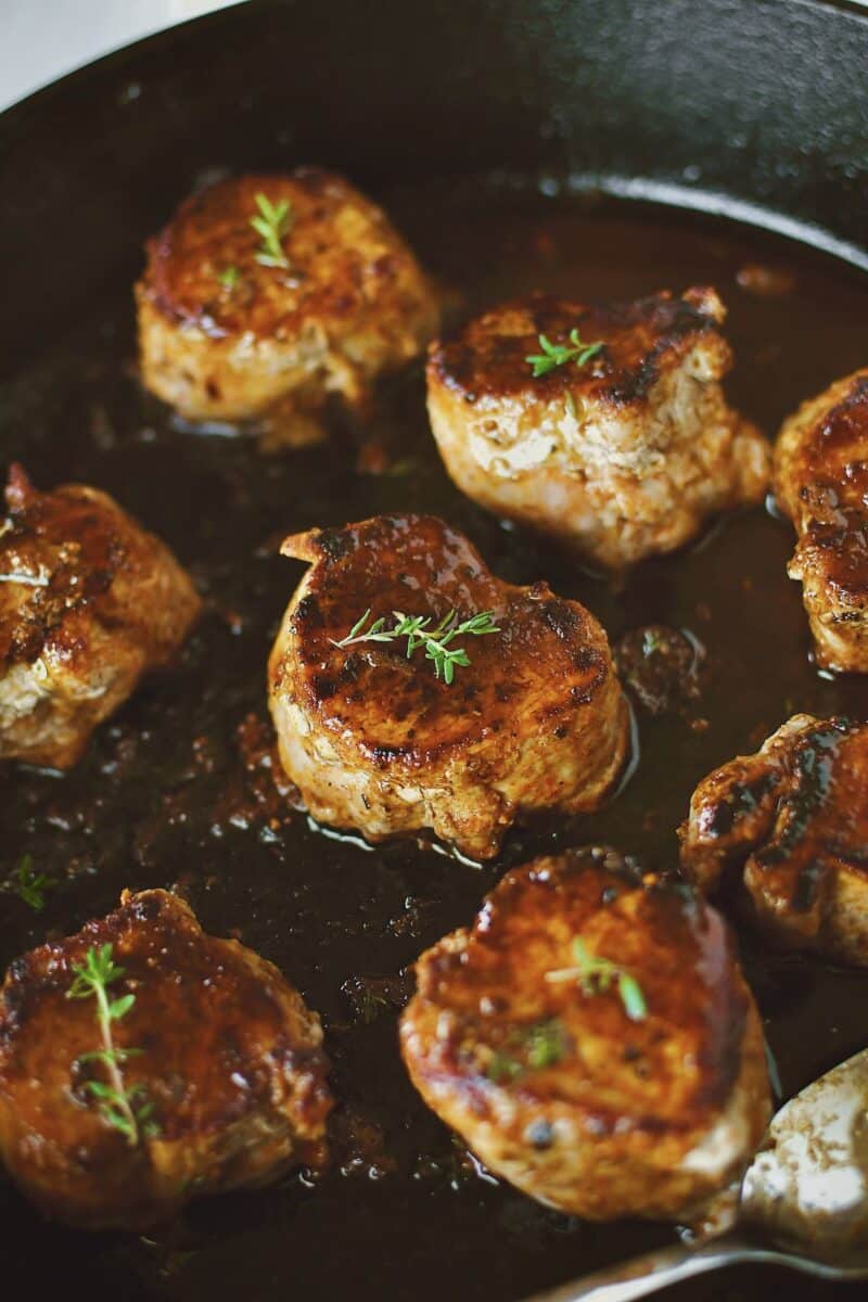 Basting the Pork Tenderloin Medallions in the pan sauce after returning them to the pan.