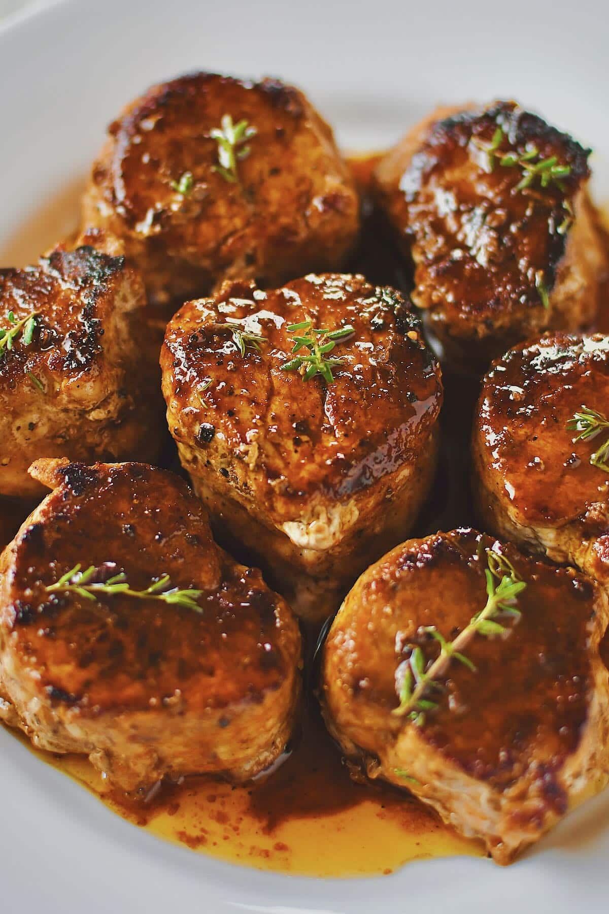 Pork Tenderloin Medallions basted with sauce and resting on a plate ready to eat.