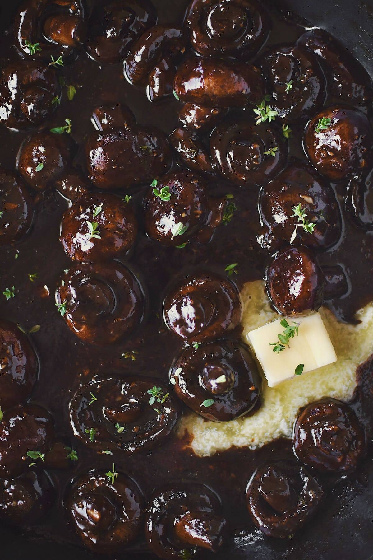 Finishing the mushrooms with a little more butter to make them extra rich and glossy. Ready to eat and topped with some thyme leaves.