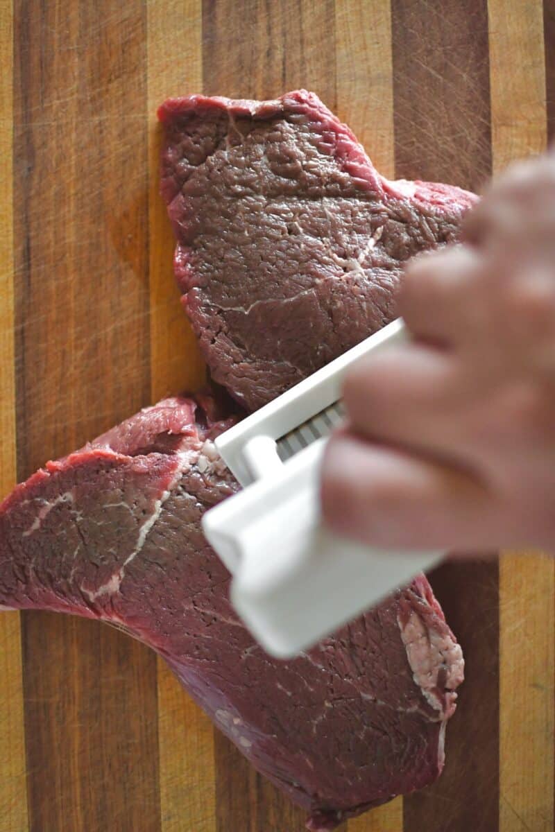 Tenderizing the sirloin steak with a jacquard meat tenderizer.