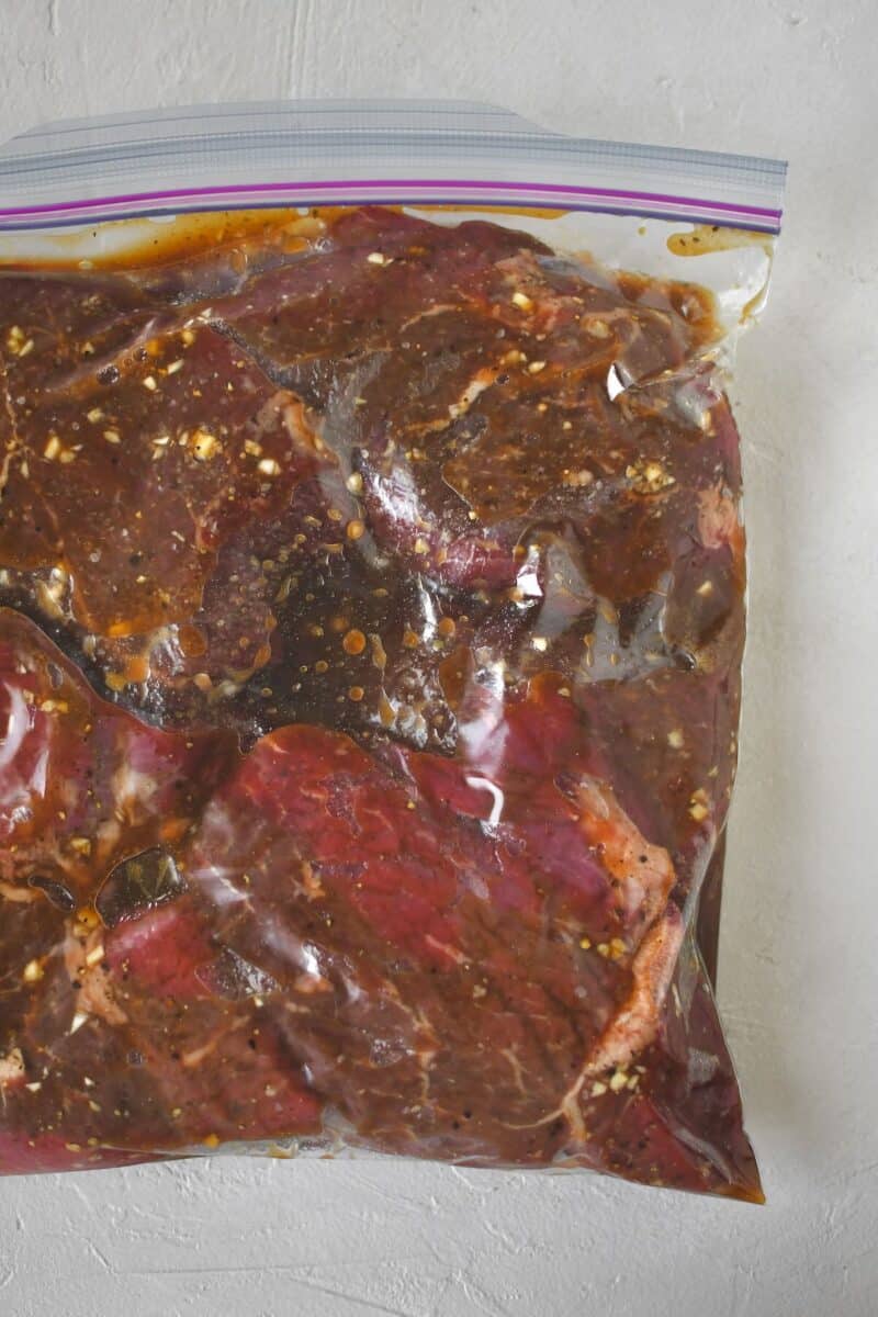 Steak and marinade mixed together in a zip-top bag ready to rest till cooked.