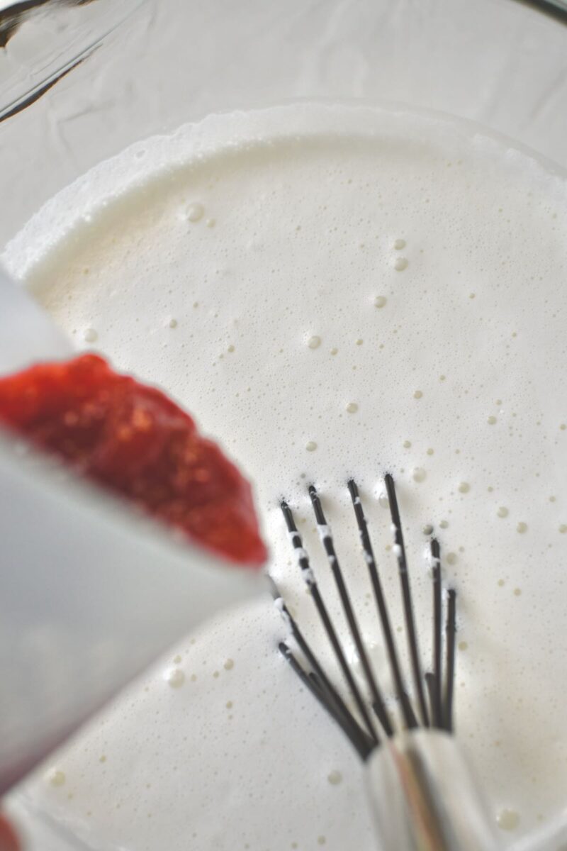 Adding the strawberry jam to the ice cream base.