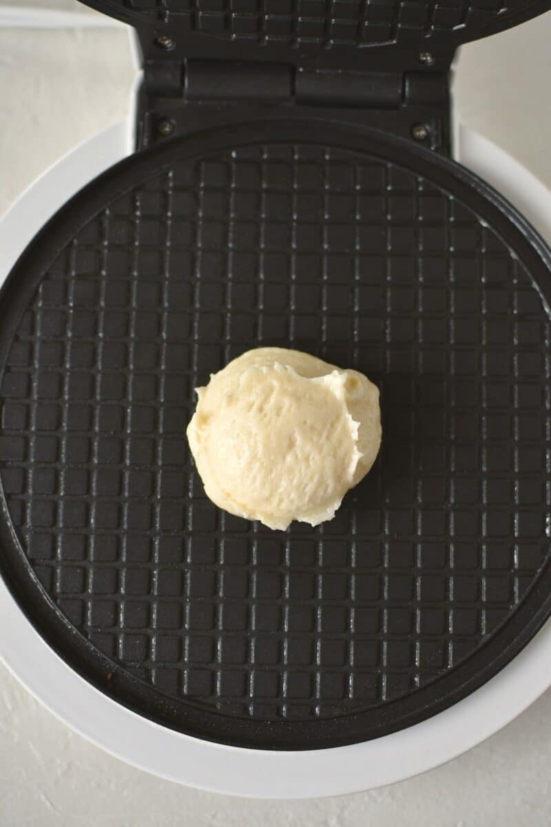 A scoop of waffle cone batter on a iron, before cooking.