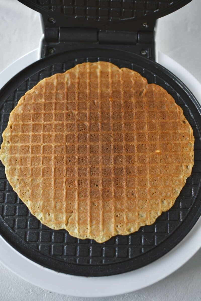 A scoop of waffle cone batter on a iron, after cooking.
