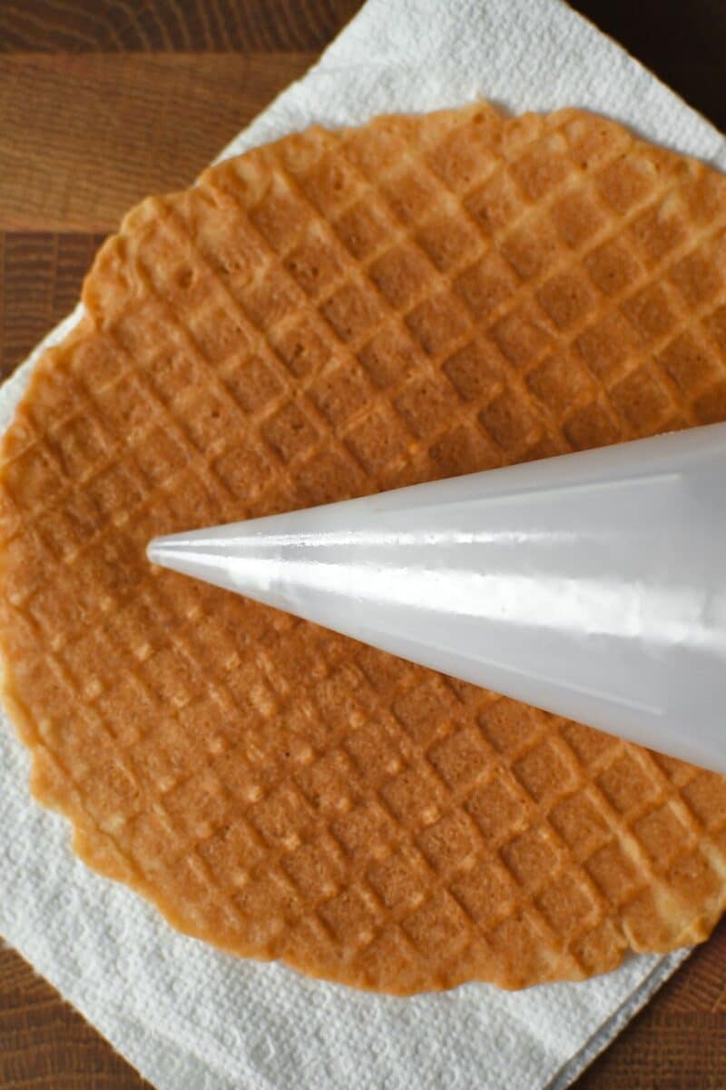 Cooked waffle removed from the iron with a cone shaper placed on it.