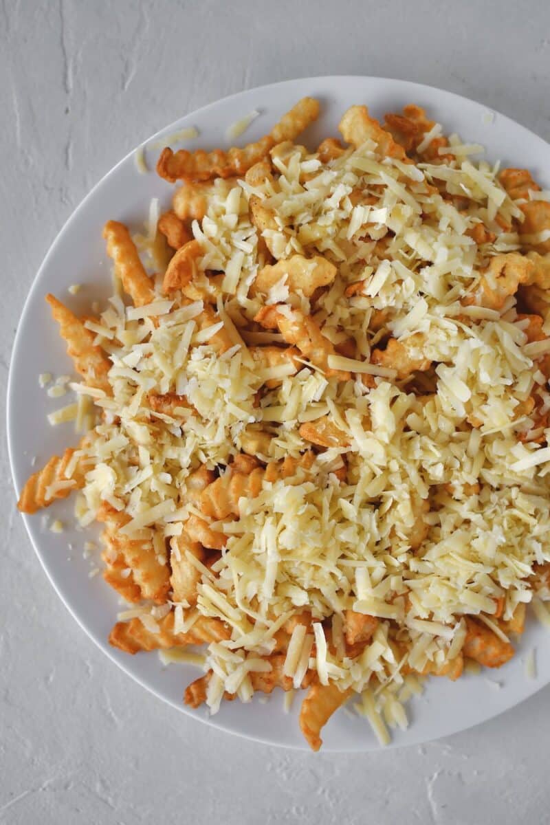 Layering irish cheddar on top of crispy crinkle french fries.