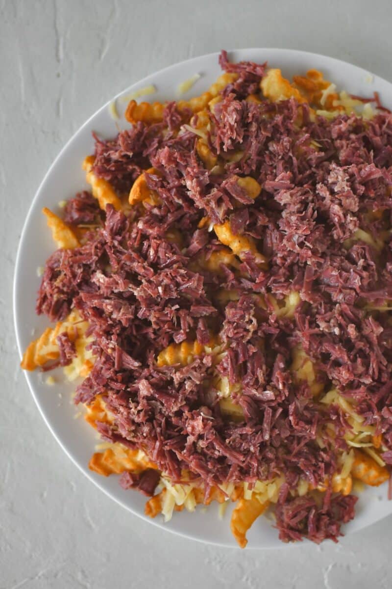 Layering warm shredded corned beef on Irish cheddar over crispy crinkle french fries.