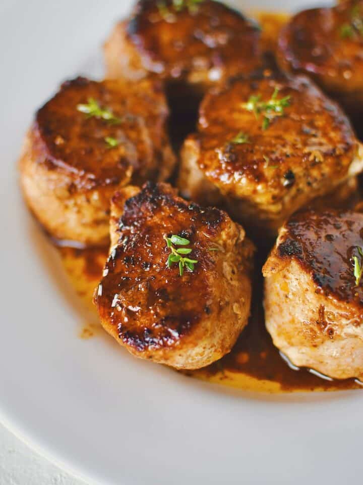 Pork Tenderloin Medallions basted with sauce and resting on a plate ready to eat.