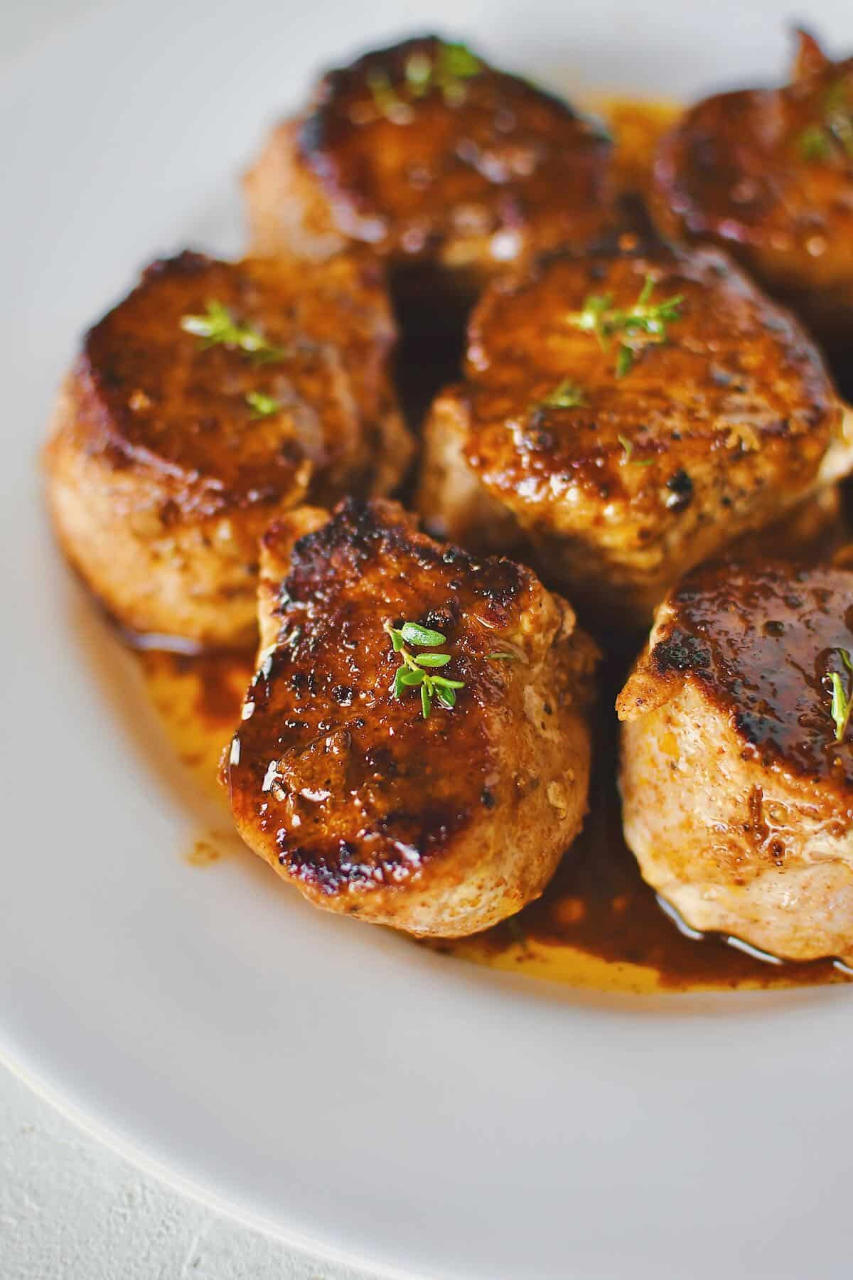 Pork Tenderloin Medallions basted with sauce and resting on a plate ready to eat.