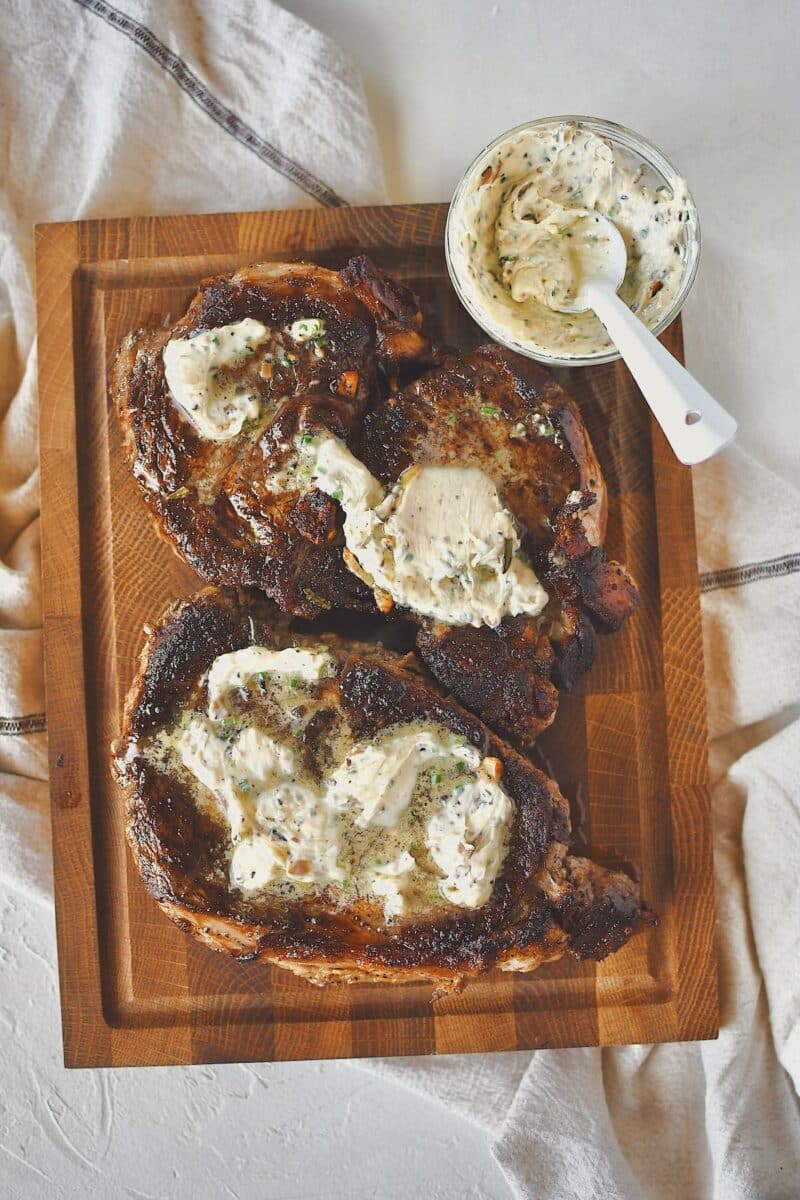 Ribeye Steaks fresh out of the pan, resting on a carving board, topped with lots of truffle butter!