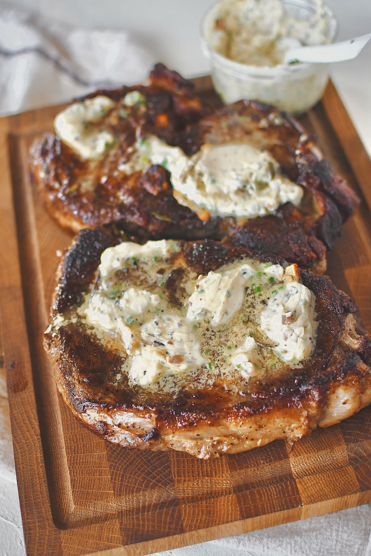 Ribeye Steaks fresh out of the pan, resting on a carving board, topped with lots of truffle butter!