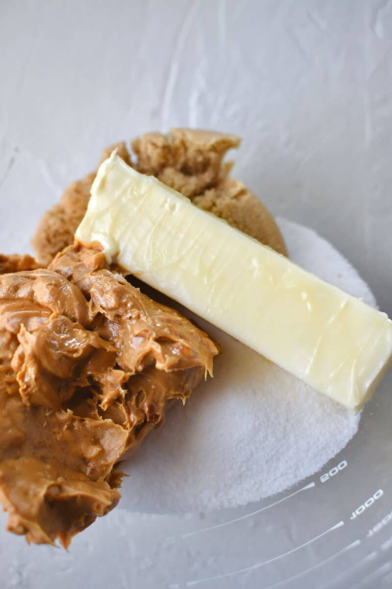 Butter, peanut butter, and sugars in a the bowl of a stand mixer ready to be creamed together.