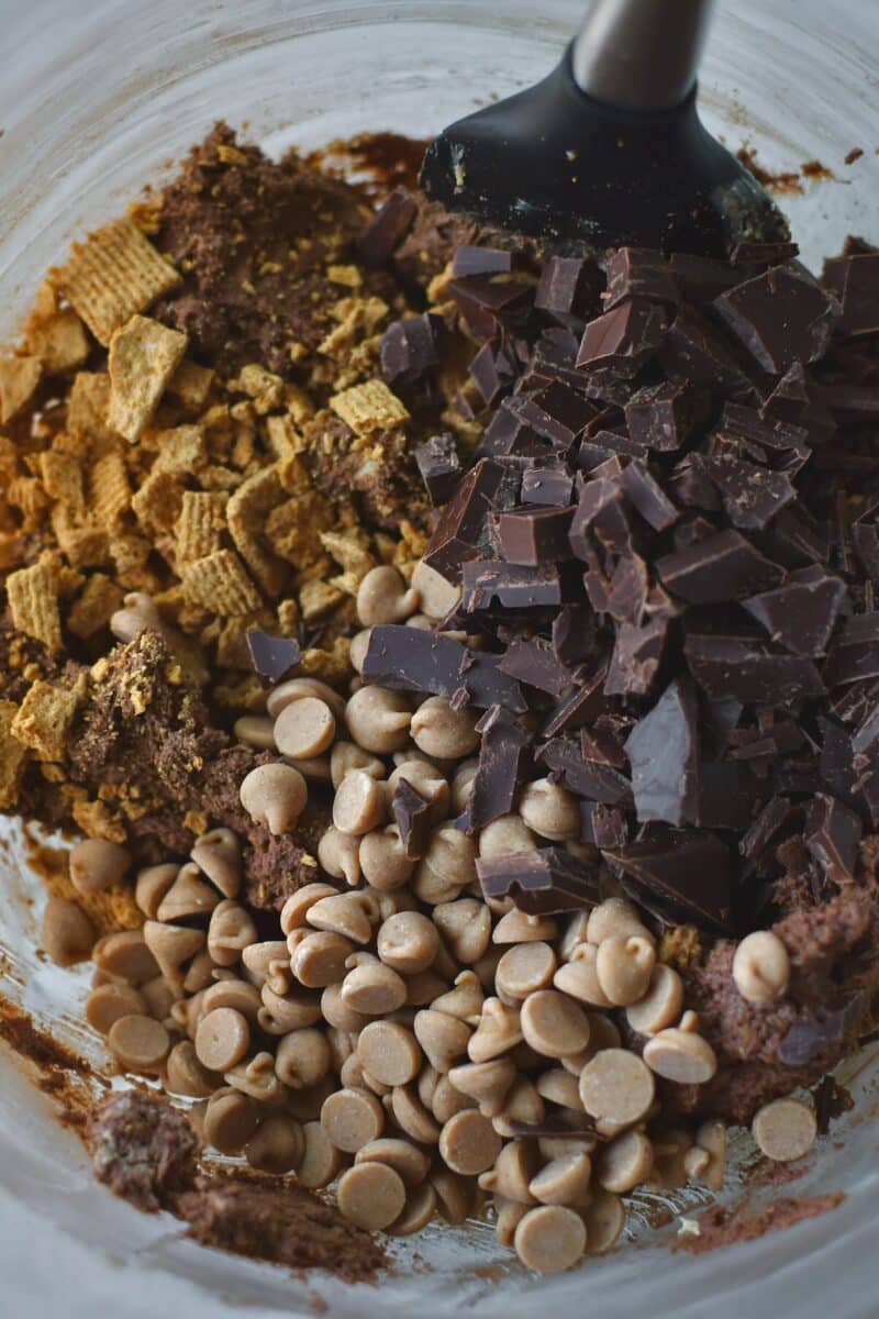 Adding the chopped chocolate bar, peanut butter chips, and crushed graham cracker cereal to the bowl.