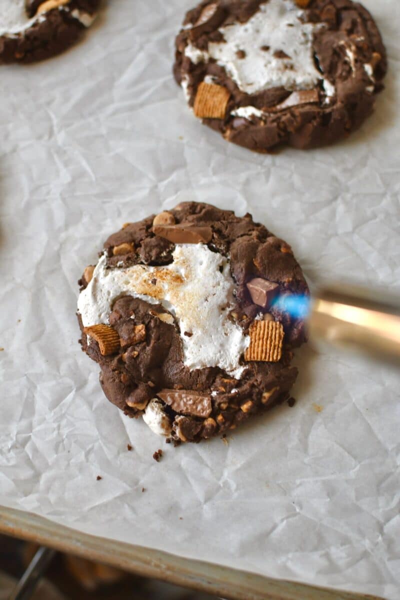 Using a kitchen torch to toast the marshmallow on some of the cookies.