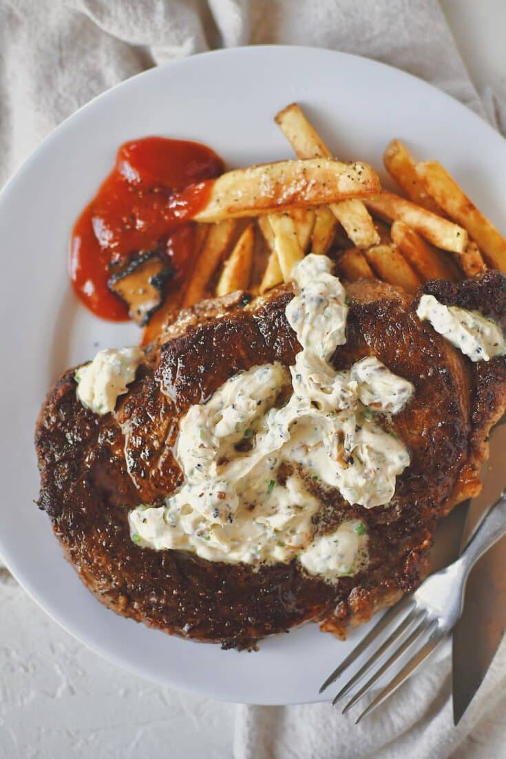Steak Frites, on a plate, the steak topped with truffle butter and the frites served with truffle chili sauce.