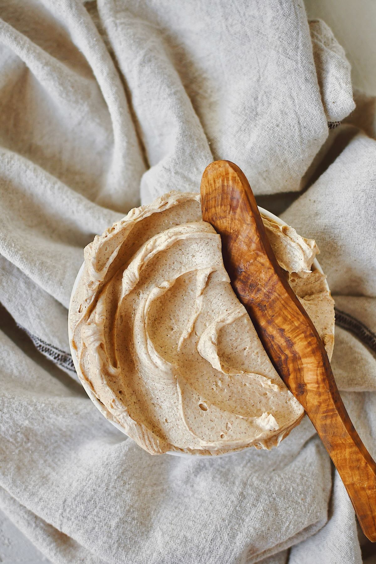 Cinnamon Butter that has been whipped to perfection, in a shallow bowl, with a wooden butter knife in it ready to be used.