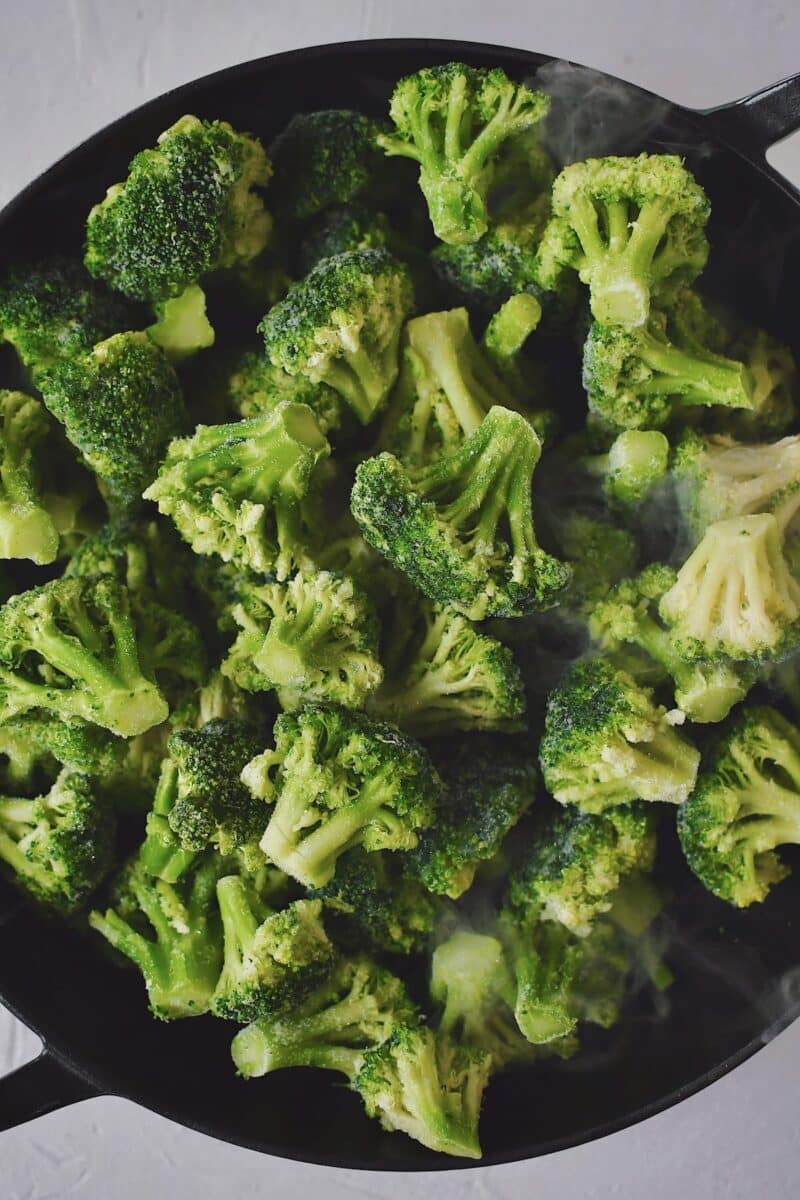 Frozen Broccoli and white wine in a large skillet that has a lid, ready to steam.