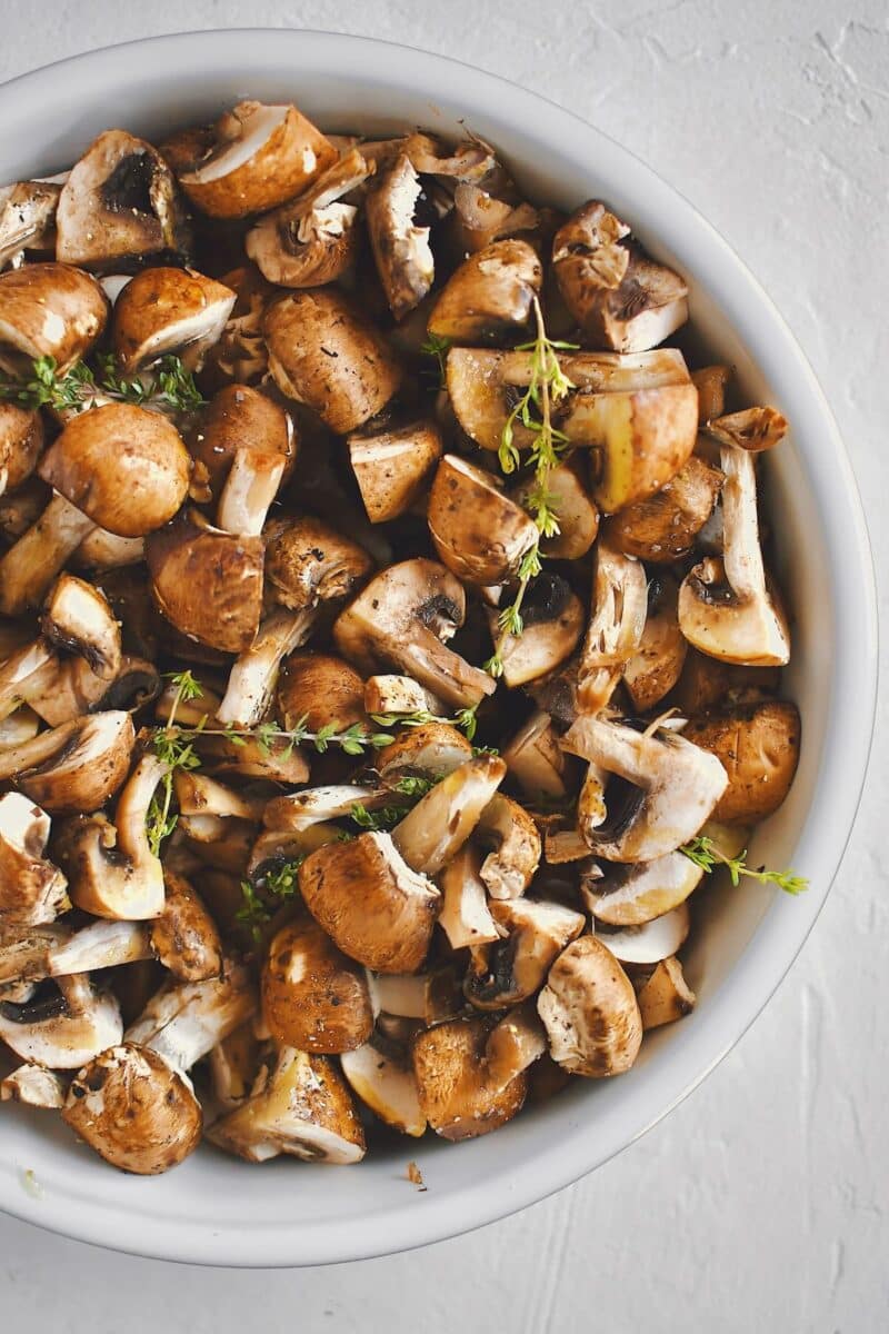 Mushrooms, tossed with olive oil, seasoning, garlic, and thyme, before roasting.