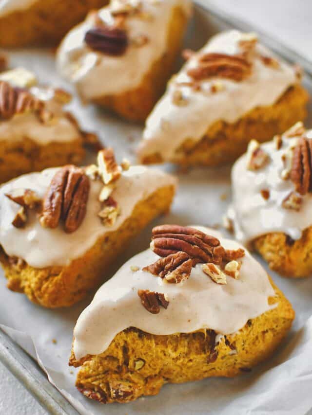 Pumpkin Scones, on a tray, topped with maple glaze and chopped pecans, ready to eat.