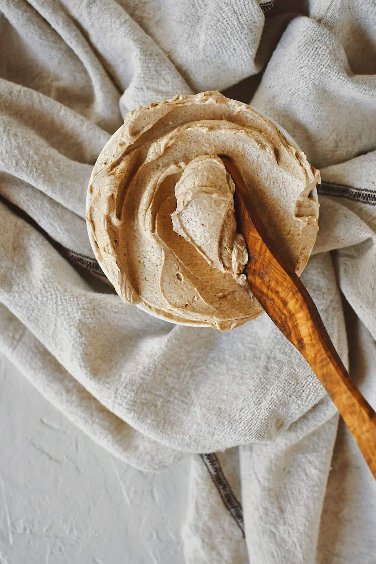 Cinnamon Butter that has been whipped to perfection, in a shallow bowl, with a wooden butter knife in it ready to be used.