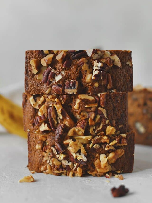 Sliced Starbucks Banana Bread Recipe stacked up with more bananas behind it, ready to eat.