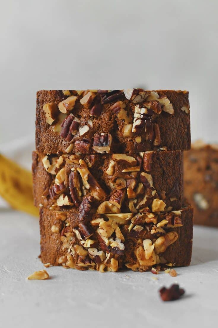 Sliced Starbucks Banana Bread Recipe stacked up with more bananas behind it, ready to eat.