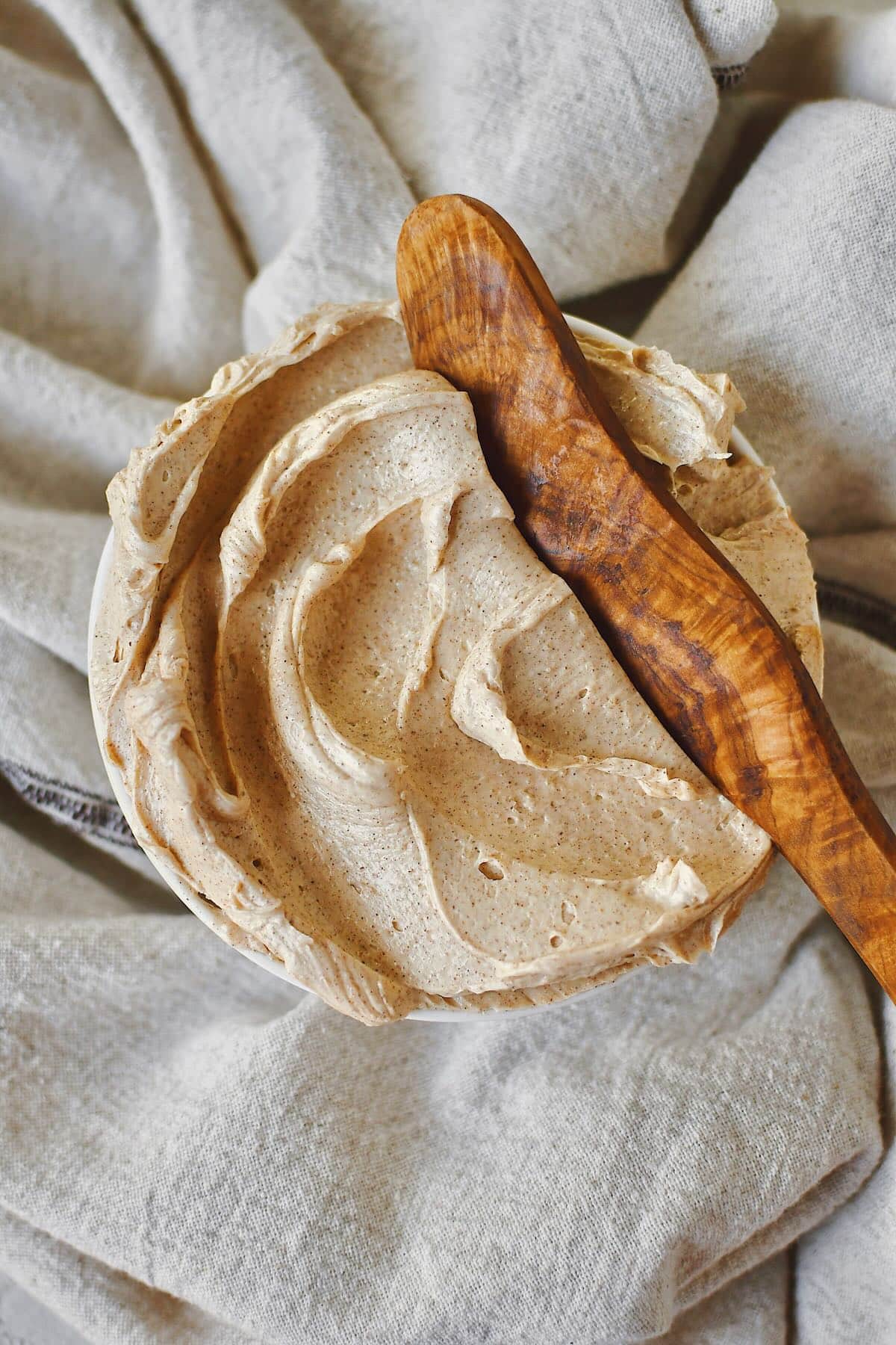 Cinnamon Butter that has been whipped to perfection, in a shallow bowl, with a wooden butter knife in it ready to be used.