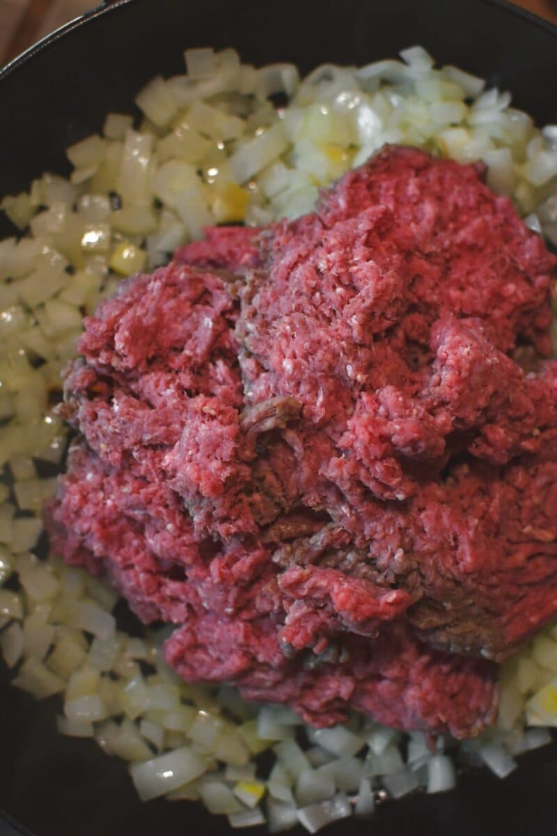 Adding the ground beef to the pan with the onions and garlic to brown.