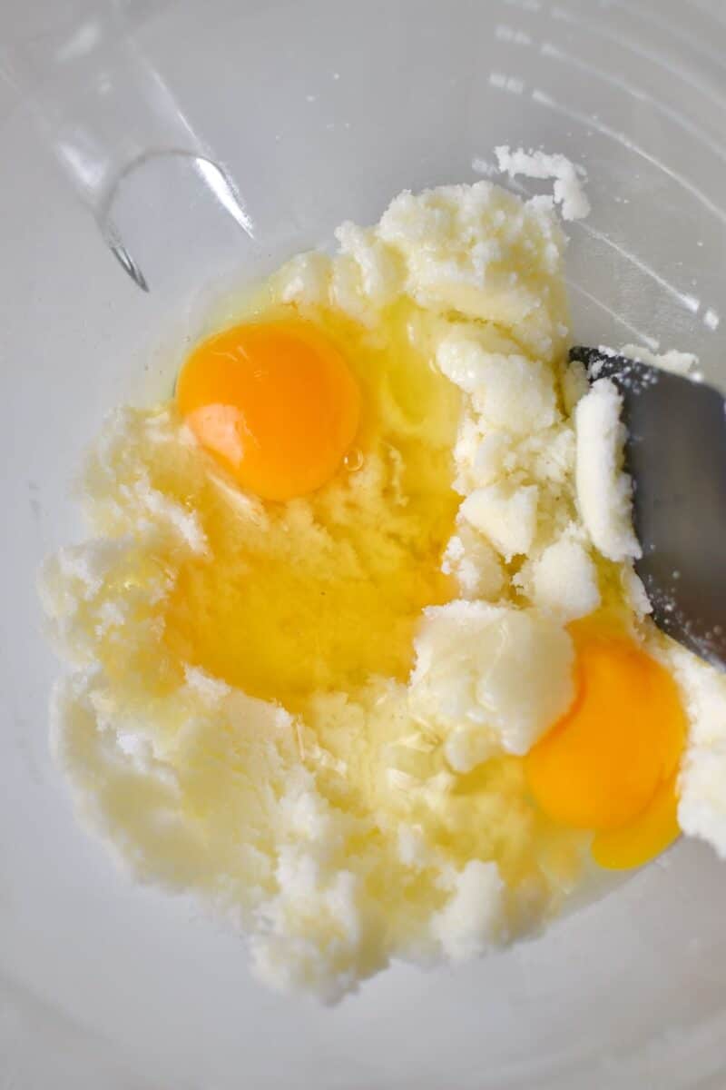 Adding the eggs and vanilla to the creamed butter and sugar.