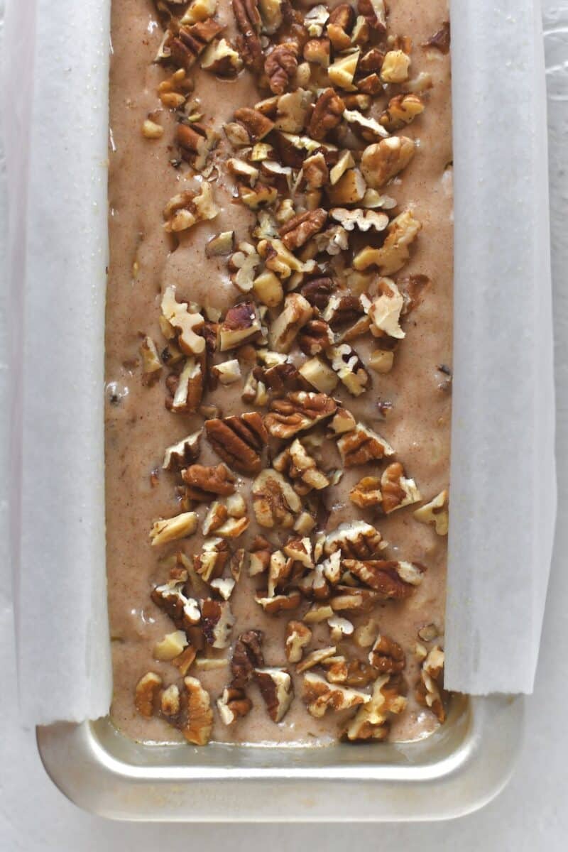 Banana bread batter in a prepared pan with parchment liner, before baking.