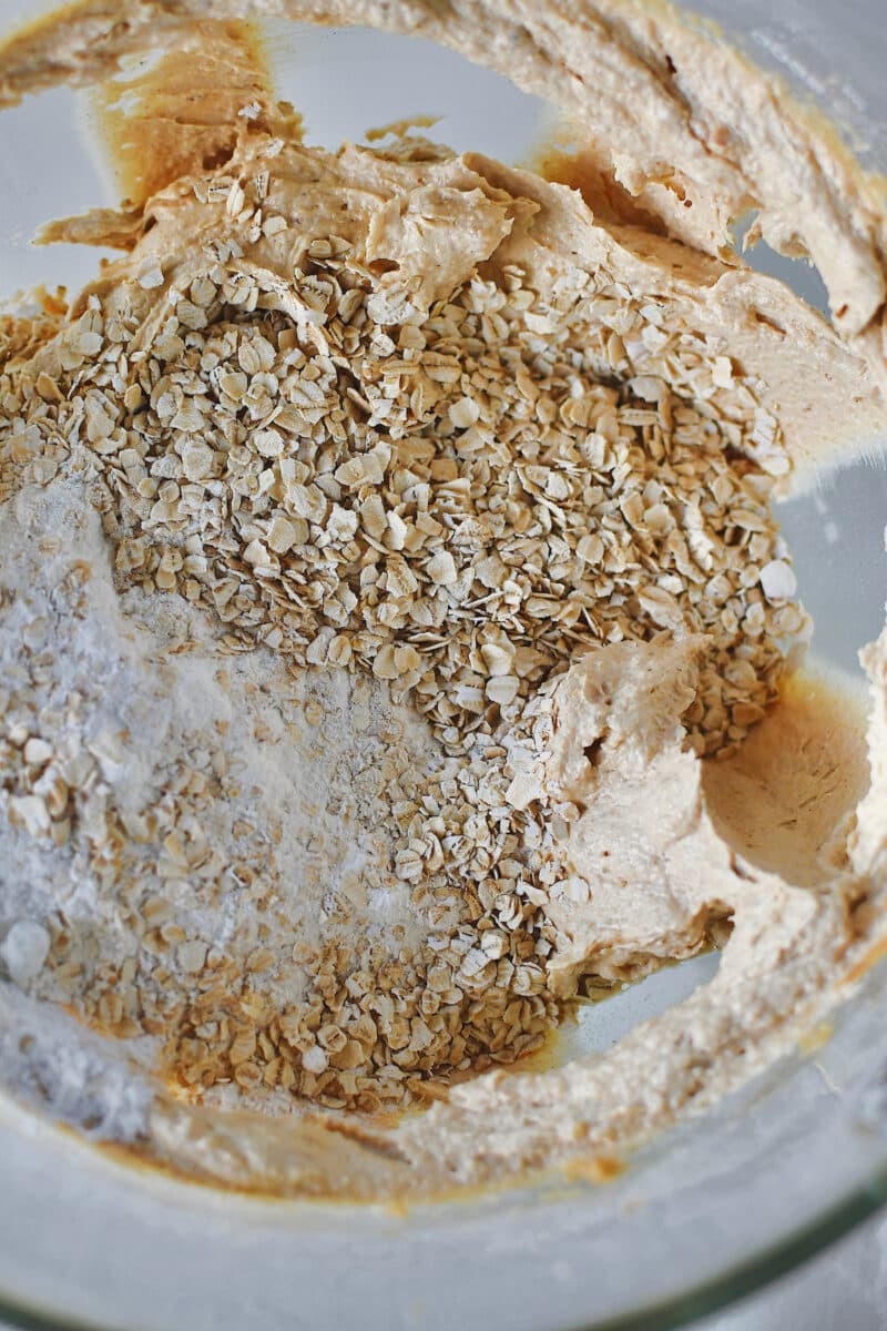 Adding the dry ingredients and oats to the creamed butters and sugars.