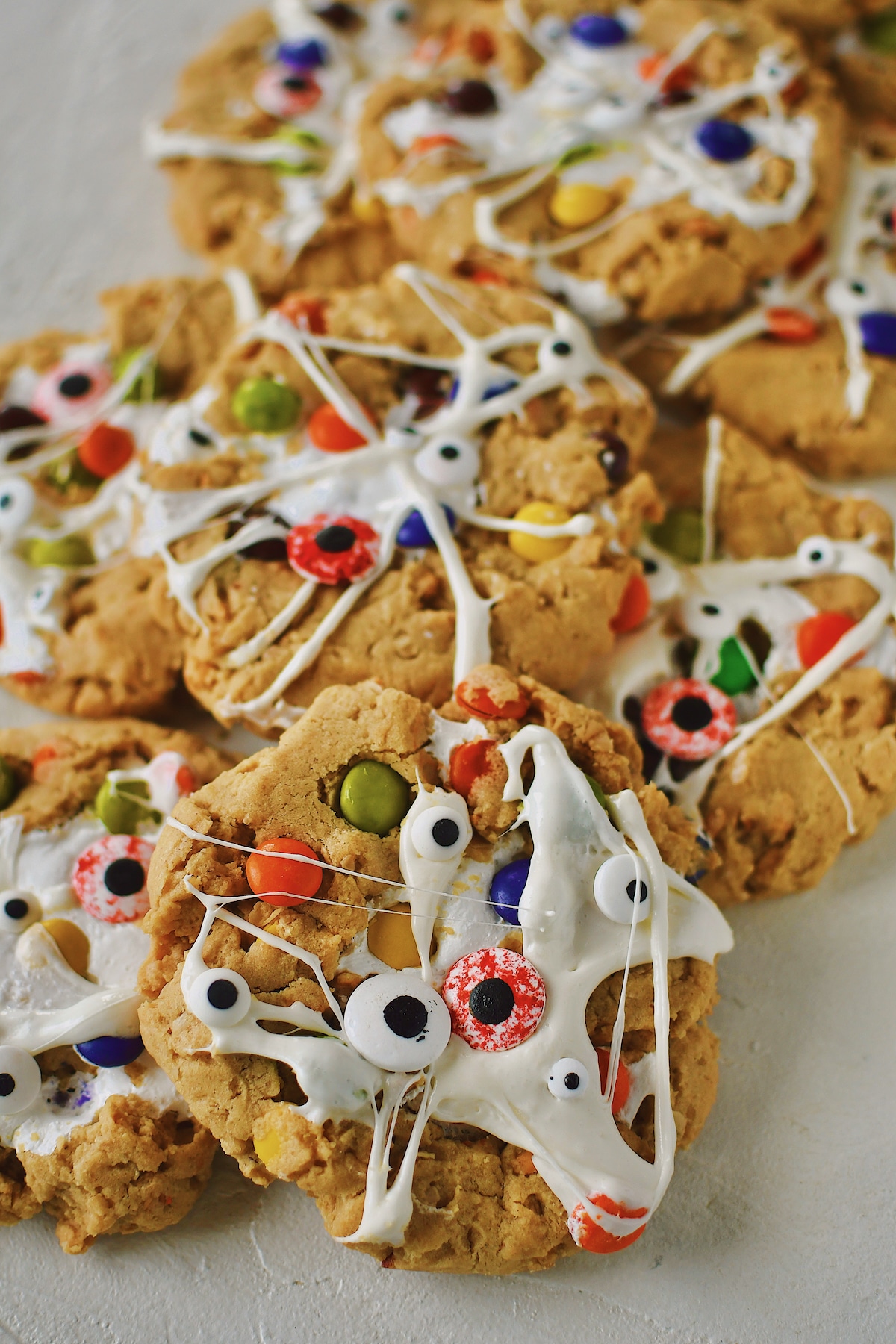 Peanut Butter Monster Cookies fresh from the oven, with melted marshmallow spread over them to look like spider webs and monster eyes added.