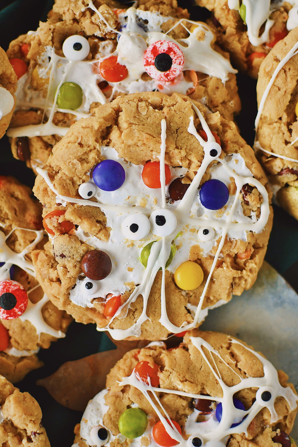 Peanut Butter Monster Cookies fresh from the oven, with melted marshmallow spread over them to look like spider webs and monster eyes added.