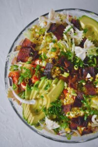 BLT Pasta Salad, topped with more of the filling ingredients, in a large bowl, ready to serve.