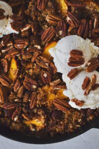 Peach Pecan Crisp, with freshly toasted pecans and vanilla ice cream scooped on top.