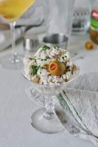 Martini Chicken Salad served in a martini glass, topped with an olive and chives.