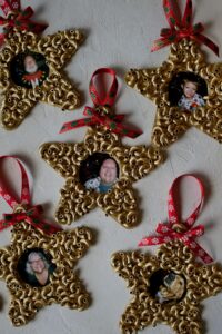 Family photos fill the easy pasta christmas ornaments, completed and sitting on the table.