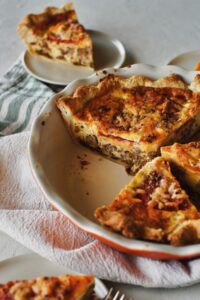 Looking into the side of a pie dish with cut cheeseburger pie, seeing all the layers.