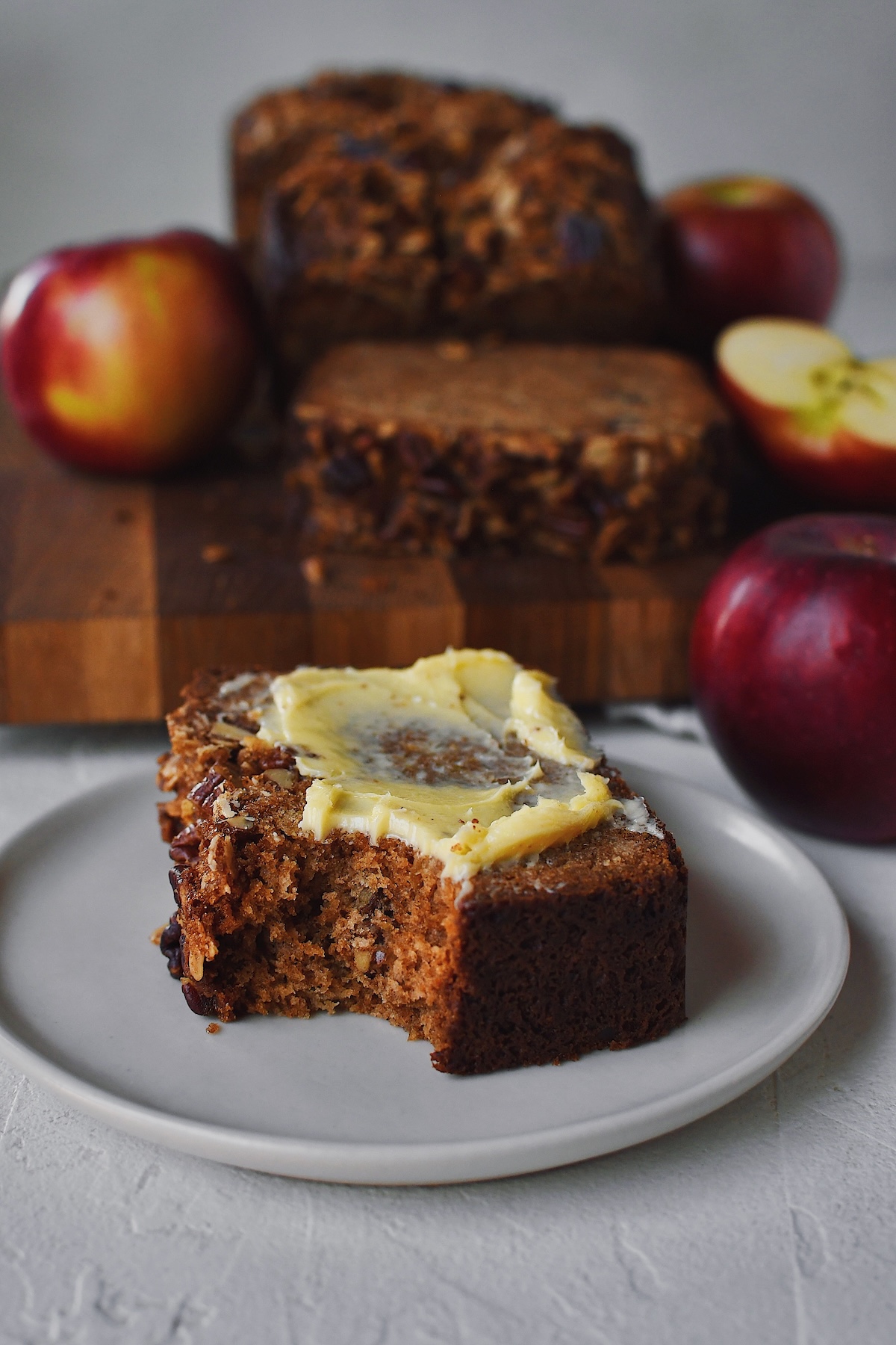 Looking into a slice of Apple Bread that has a bite taken out of it and butter spread on top.