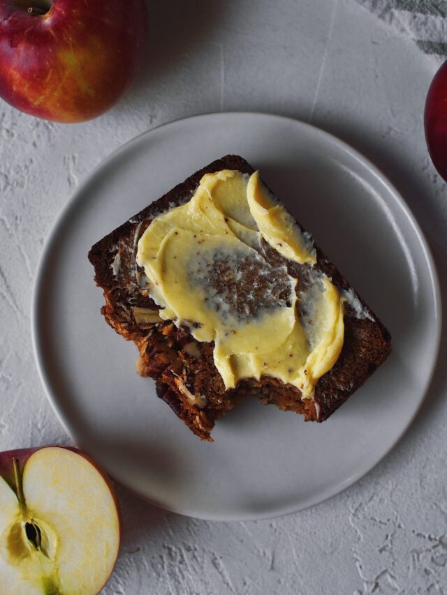 Looking Down at a slice of Apple Bread that has a bite taken from it and butter spread over the top.