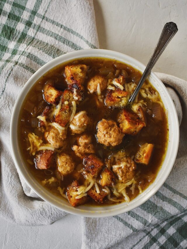 Looking down into a bowl of Cheesy French Onion Soup - Kendell's Version, filled with mini chicken meatballs, and gruyere croutons.
